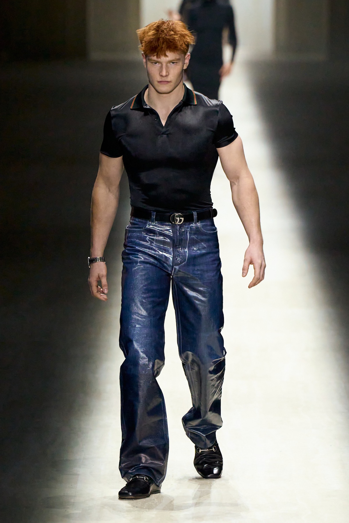 Model na wybiegu Gucci w czarnej koszulce polo i błyszczących jeansach – kolekcja męska Gucci