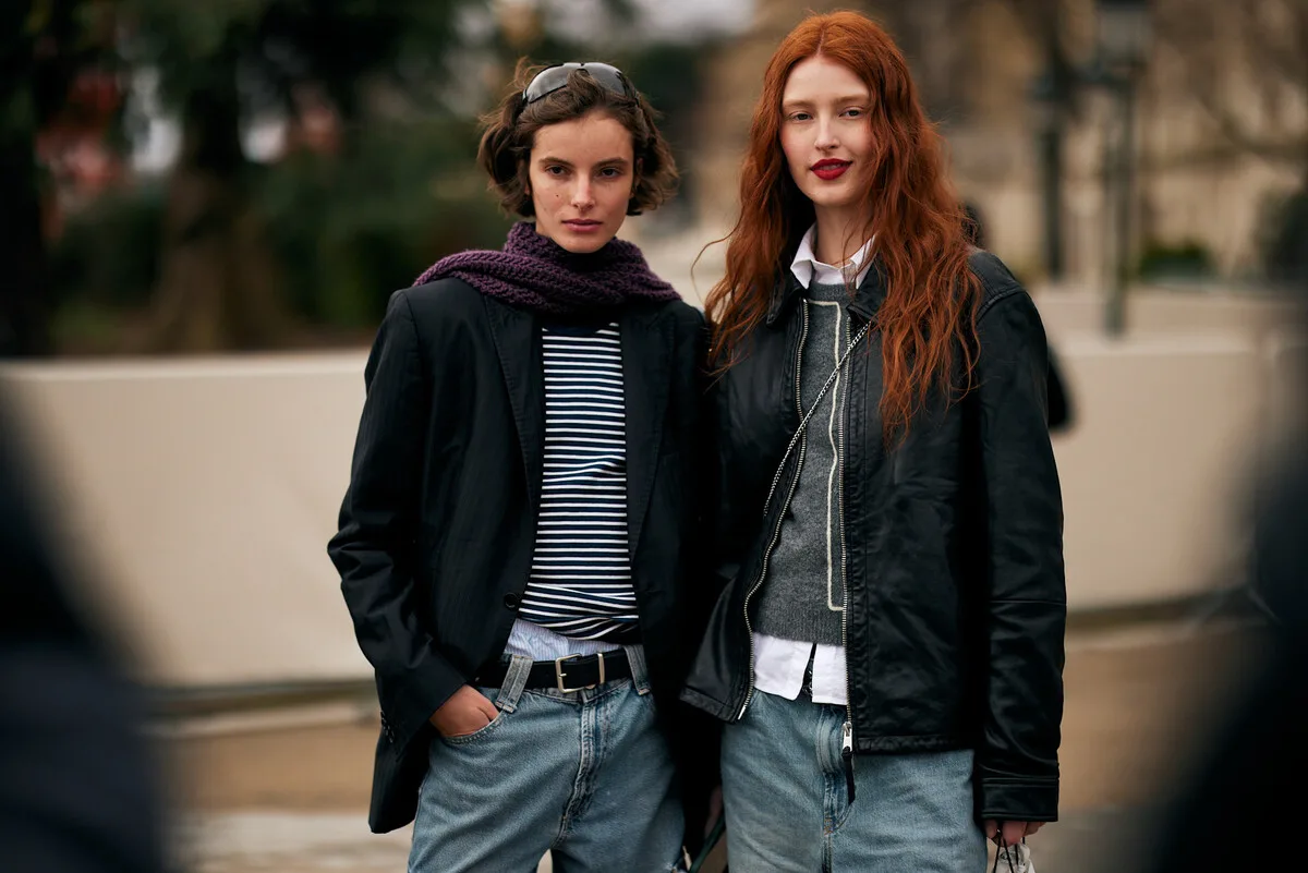 Dwie młode kobiety w stylizacjach czerpiących inspirację z mody ulicznej pozują na ulicy miejskiej, demonstrując swobodne, modne stroje. Ich wizerunek odzwierciedla stylistykę popularną wśród generacji Z, do której adresuje swoją ofertę firma Edikted. To przykład stylu, który brand transferuje z przestrzeni online do świata fizycznego wraz z inauguracją pierwszego salonu w Europie.