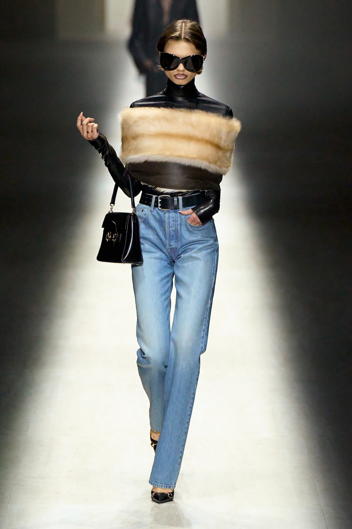 Modelka Gucci w okularach przeciwsłonecznych, futrzanym topie i jeansach – pokaz mody Gucci