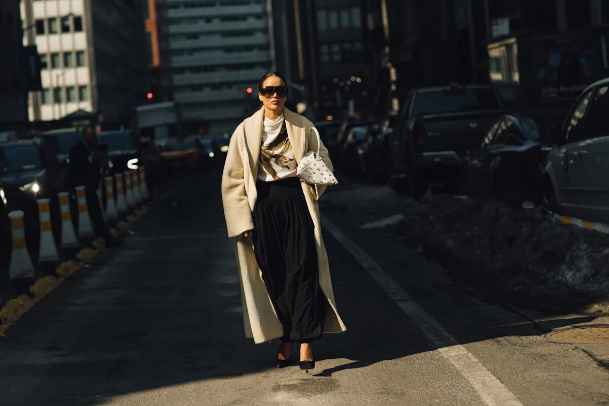 Podwyżki cen ubrań 2026. Elegancka kobieta na ulicy w szykownym płaszczu ilustruje zmieniający się sektor modowy w obliczu wzrostu cen odzieży w 2026 roku. Zwiększone nakłady produkcji i materiałów powodują, że kupujący częściej decydują się na jakość niż na ilość.