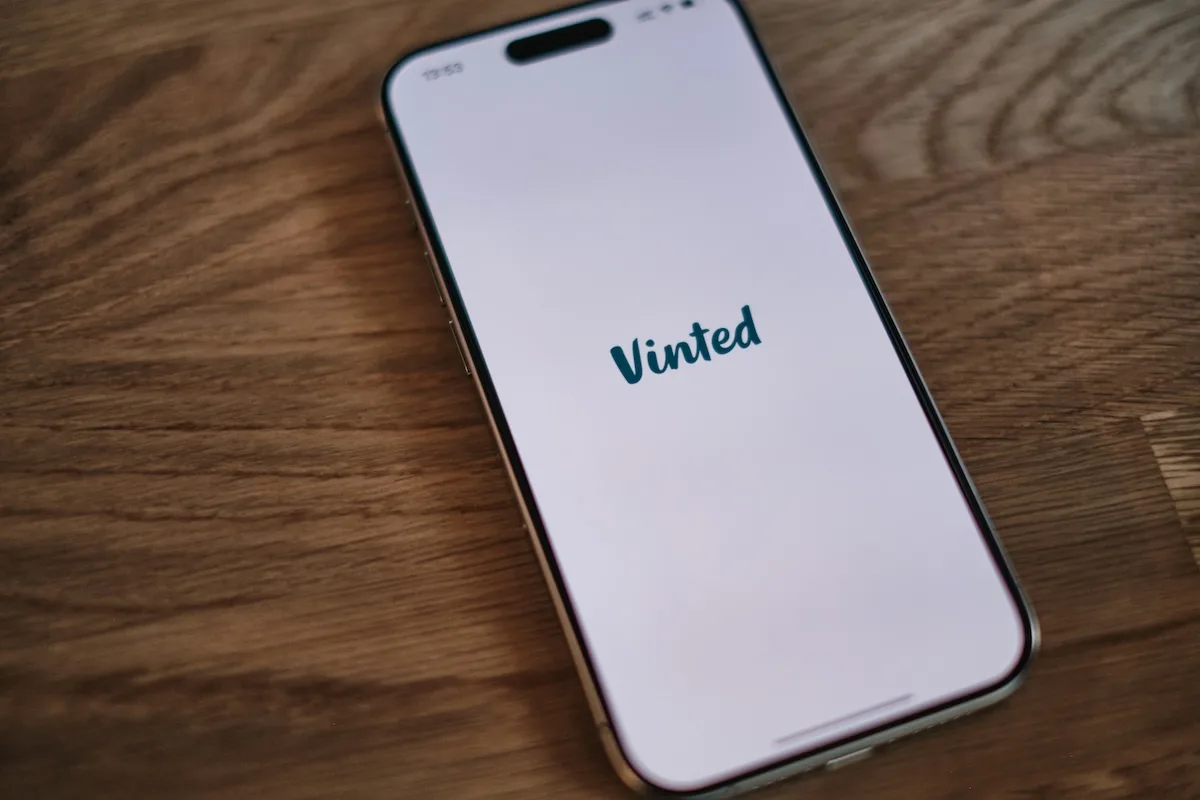 Smartfon z otwartą aplikacją Vinted, gdzie dostępna jest funkcja zapraszania znajomych. To właśnie przez profil użytkownika można wygenerować link do programu rekomendacji Vinted i zdobywać vouchery. Zdjęcie odnosi się do nowej funkcji pozwalającej zarobić do 60 zł za polecenia.