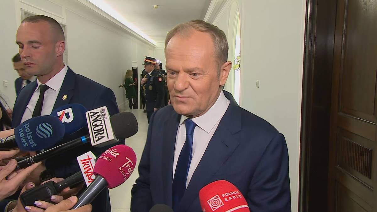 Donald Tusk przemawia do dziennikarzy otoczony mikrofonami.