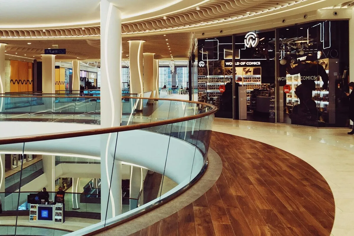 Alfa Centrum Gdańsk. Nowoczesna powierzchnia obiektu handlowego z szklanymi barierkami i sklepami w tle – zdjęcie ilustracyjne. Tego rodzaju budynki coraz częściej ulegają likwidacji i rozbiórce w związku ze zmianami zachodzącymi na obszarze handlu. W ich zamian powstają nowe przedsięwzięcia, głównie mieszkaniowe.