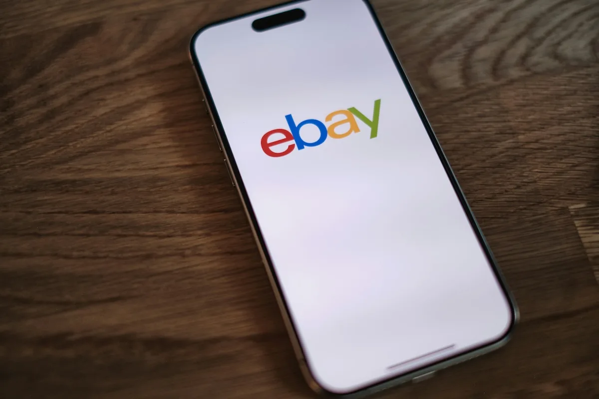 Logo eBay wyświetlone na ekranie smartfona. GameStop zamierza nabyć eBay w transakcji szacowanej na 56 mld dolarów, a Ryan Cohen anonsuje budowę konkurenta dla Amazona i rywalizację o rynek e-commerce.