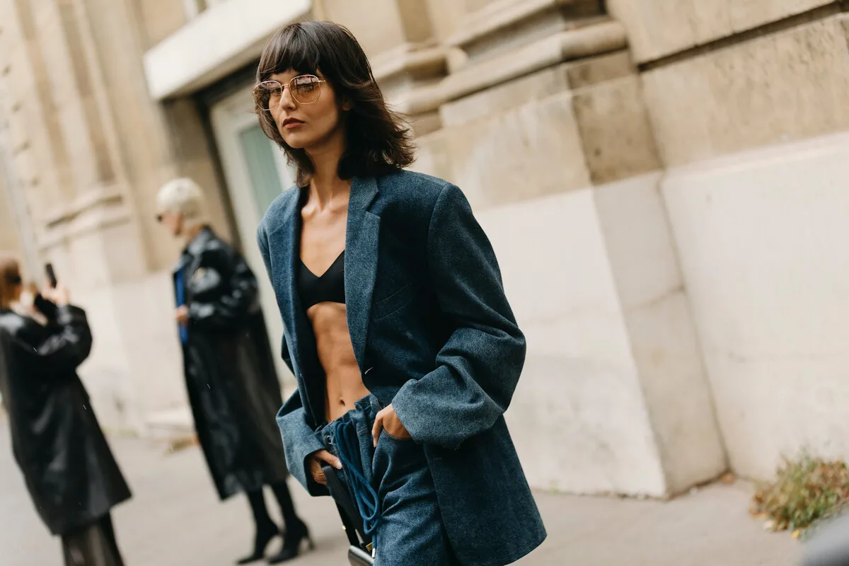 UOKiK H&amp;M Peek &amp; Cloppenburg. Dama w ciemnoniebieskim zestawie ubrań ulicznych pozuje na tle miasta podczas tygodnia mody. Fotografia ilustruje zagadnienie przecen i ofert specjalnych w butikach odzieżowych oraz działań UOKiK w stosunku do rozpoznawalnych firm odzieżowych.