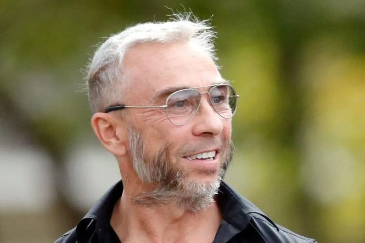 James Holder uznany za winnego. Na fotografii widoczny jest uśmiechnięty mężczyzna w okularach, z krótkimi posiwiałymi włosami i zarostem. Ten portret ilustruje artykuł dotyczący procesu sądowego związanego ze współtwórcą marki Superdry.