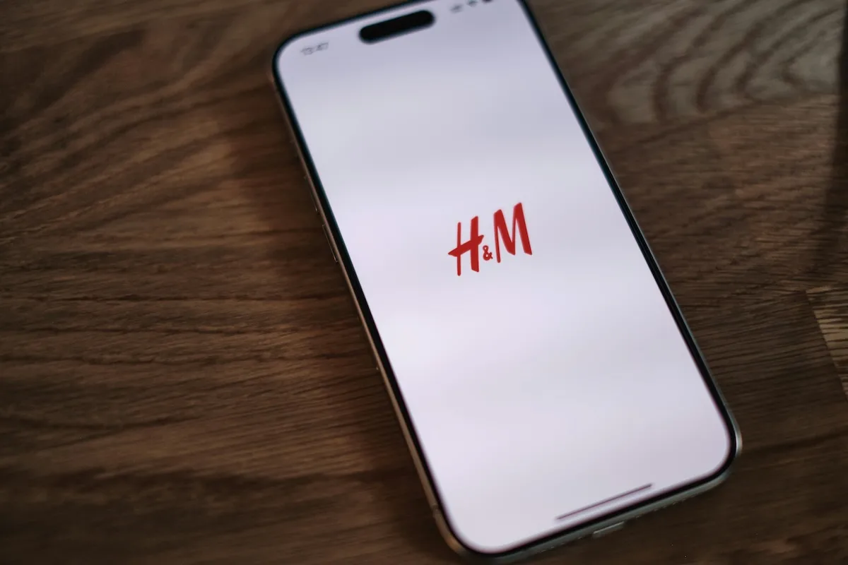 H&amp;M wyprzedaż online 2026 - kiedy start? Na zdjęciu telefon z logo H&amp;M na ekranie. 