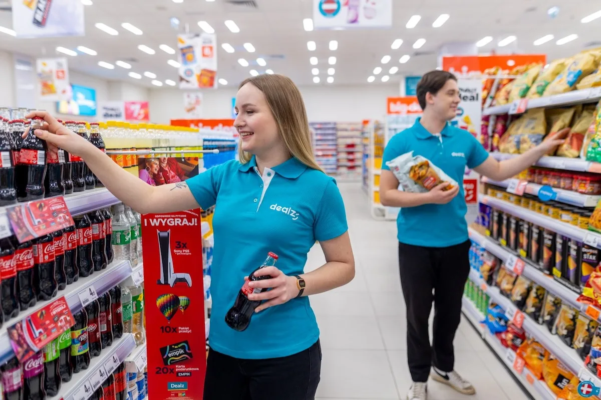 Pracownicy Dealz układają produkty na półkach.