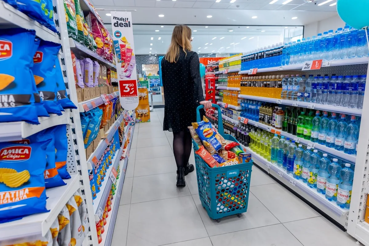 Dealz - kobieta robi zakupy, chodzi między półkami z koszykiem.