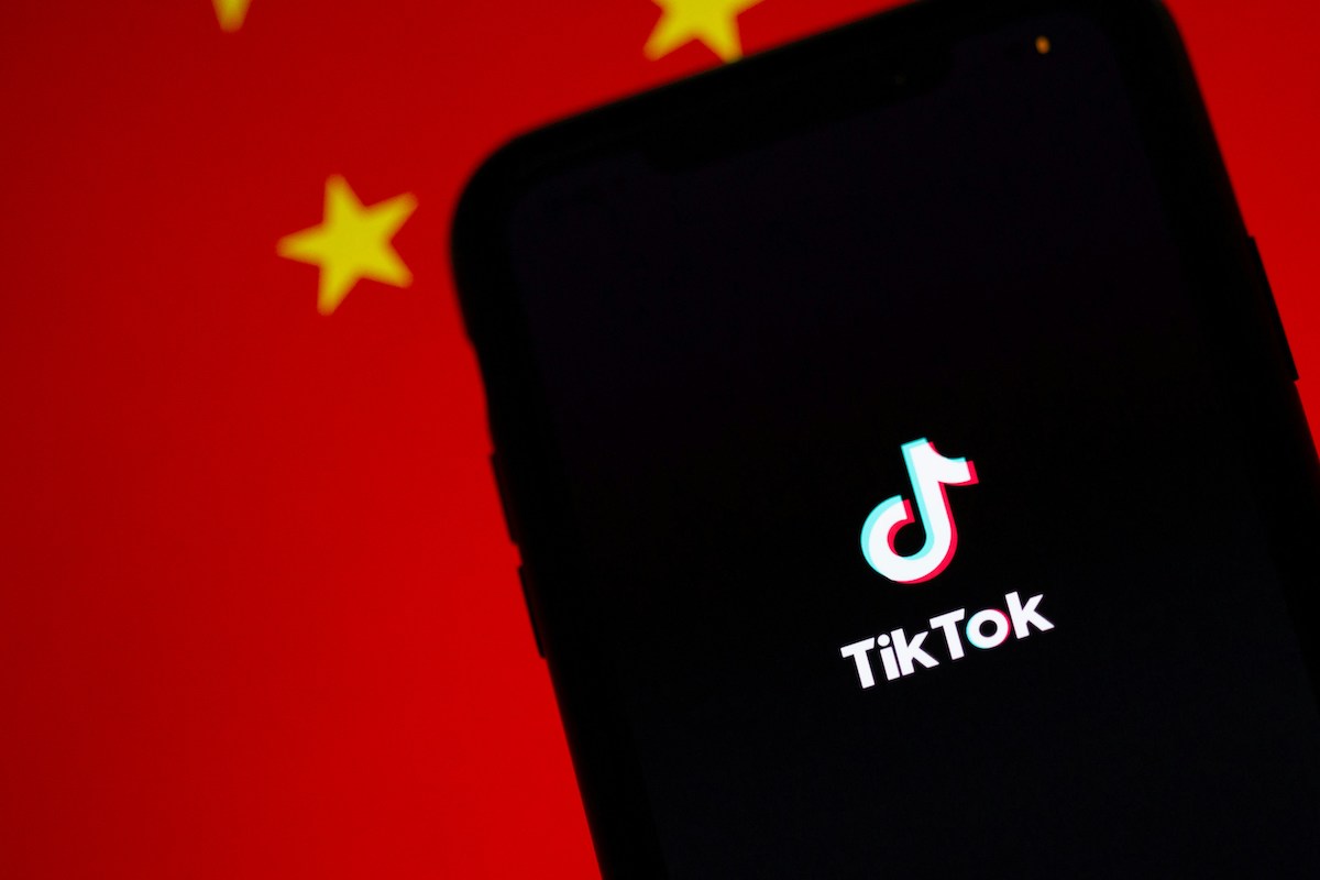 Logo TikTok na ekranie telefonu komórkowego na tle flagi Chin. Chińska aplikacja RedNote może zostać alternatywą dla TikToka.