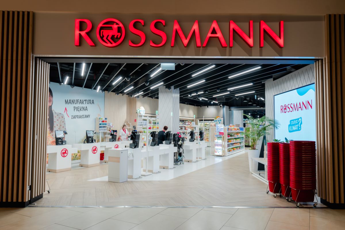 Zdjęcie przedstawia nowoczesne wnętrze drogerii Rossmann, z elegancko zaprojektowanymi kasami oraz jasno oświetlonymi regałami pełnymi produktów. Wystrój sklepu podkreśla dbałość firmy o estetykę i wygodę klientów. Tego typu placówki są istotnym elementem sukcesu i rekordowych wyników sieci Rossmann, które w 2024 roku osiągnęły historyczne obroty.